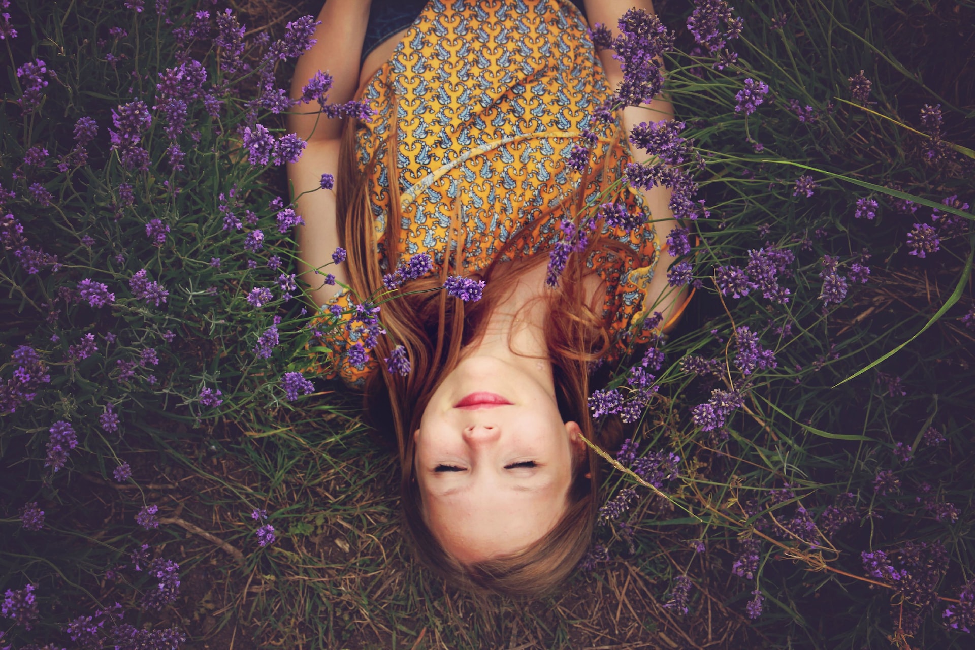 woman in yellow and teal top sleeping beside lavenders